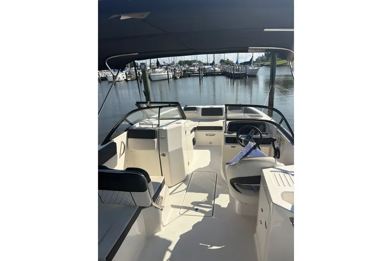 Slide: The Image of 2023 Bayliner DX 2200 boat interior with helm, docked at marina. - 3