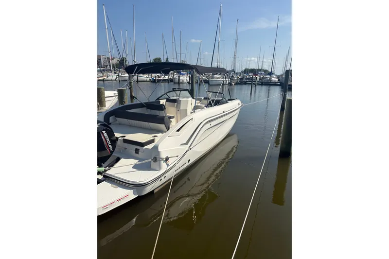 Slide: The Image of 2023 Bayliner DX 2200 boat docked in a marina under clear blue skies. - 1