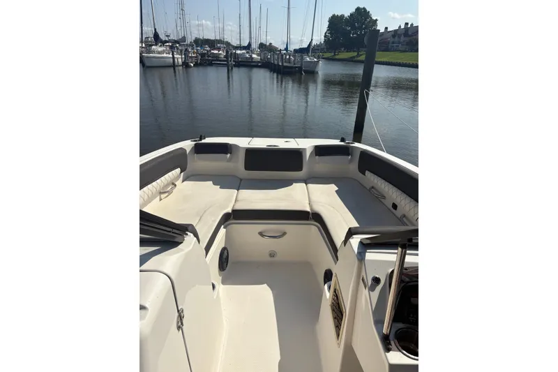 Slide: The Image of 2023 Bayliner DX 2200 boat interior at marina, featuring spacious seating and calm waters. - 7