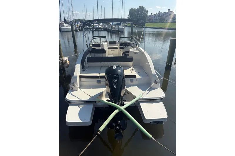 Slide: The Image of 2023 Bayliner DX 2200 boat docked in a marina, rear view. - 2