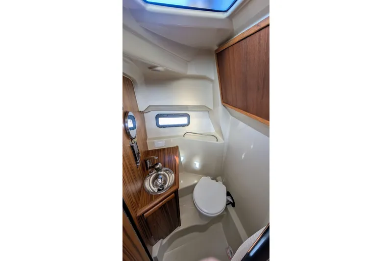 Slide: The Image of Compact bathroom in 2022 Ranger Tugs R-25 boat with wood accents and stainless steel sink. - 12