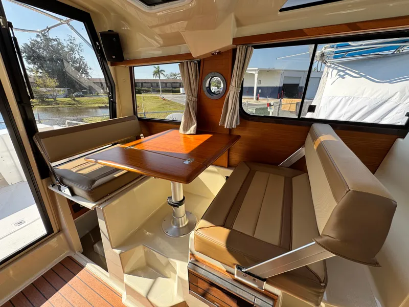 Slide: The Image of 2022 Ranger Tugs R-25 interior with dining area, featuring wood table and cushioned seating. - 8