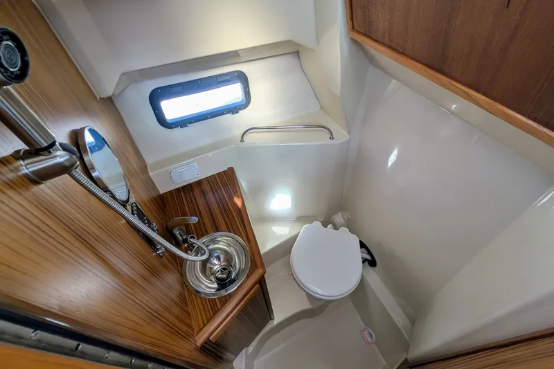 Slide: The Image of 2022 Ranger Tugs R-25 boat bathroom with compact sink, toilet, and window. - 13