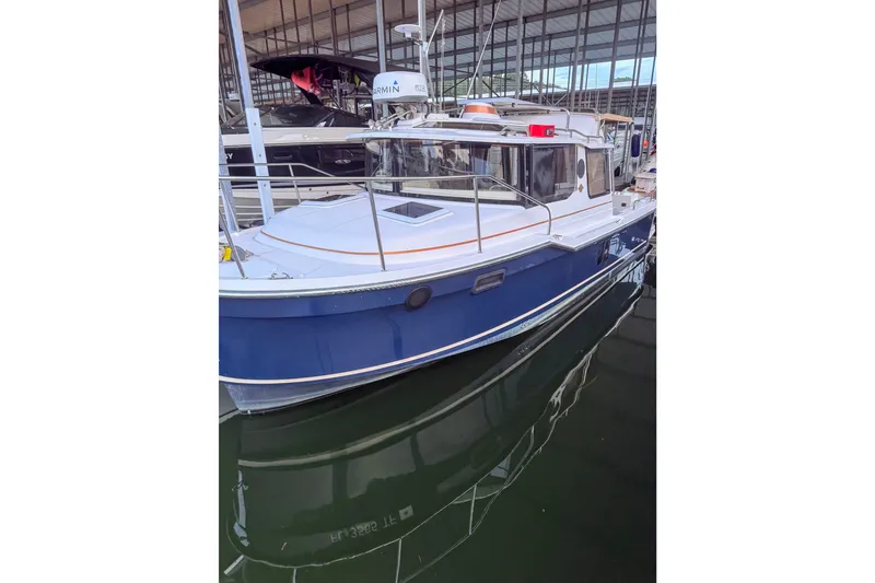 Slide: The Image of 2022 Ranger Tugs R-25 boat docked in a marina, featuring a sleek blue hull. - 0