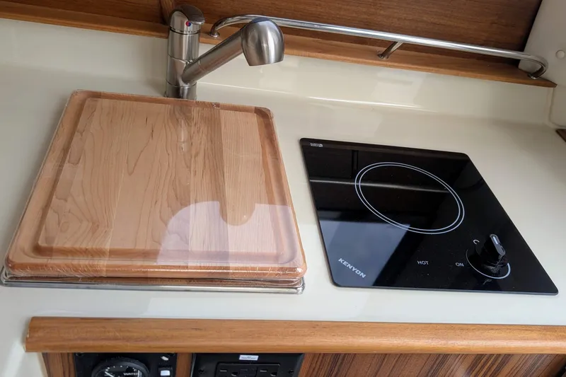 Slide: The Image of Modern kitchen area in 2022 Ranger Tugs R-25 with stove and wooden cutting board. - 10