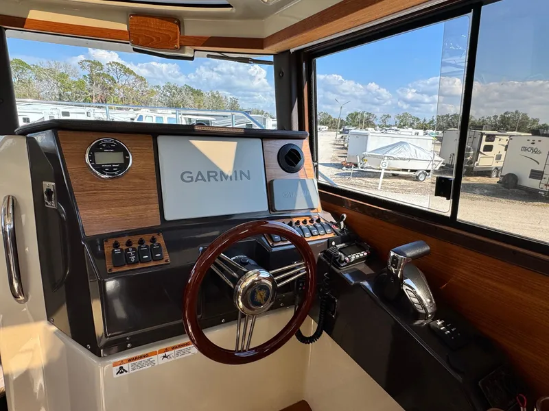 Slide: The Image of 2022 Ranger Tugs R-25 helm with Garmin navigation system, steering wheel, and control panel. - 11