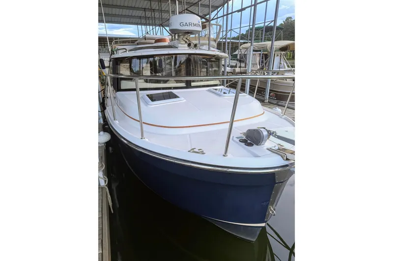 Slide: The Image of 2022 Ranger Tugs R-25 boat docked in a marina, featuring a blue hull and Garmin equipment. - 1