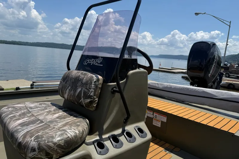 Slide: The Image of 2022 Tracker Grizzly 1860 CC boat with camo seats, docked by a scenic lake. - 15