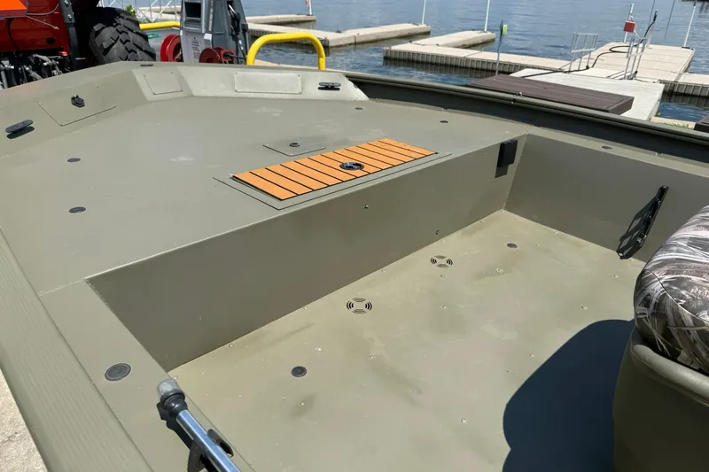 Slide: The Image of 2022 Tracker Grizzly 1860 CC boat interior at a dockside, showcasing spacious deck layout. - 14