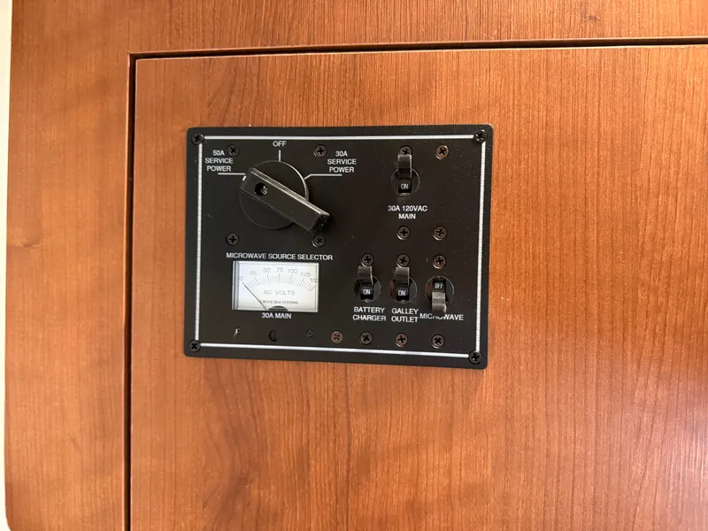 Slide: The Image of An electrical control panel on a boat with switches and a dial, set in a wood panel. - 38