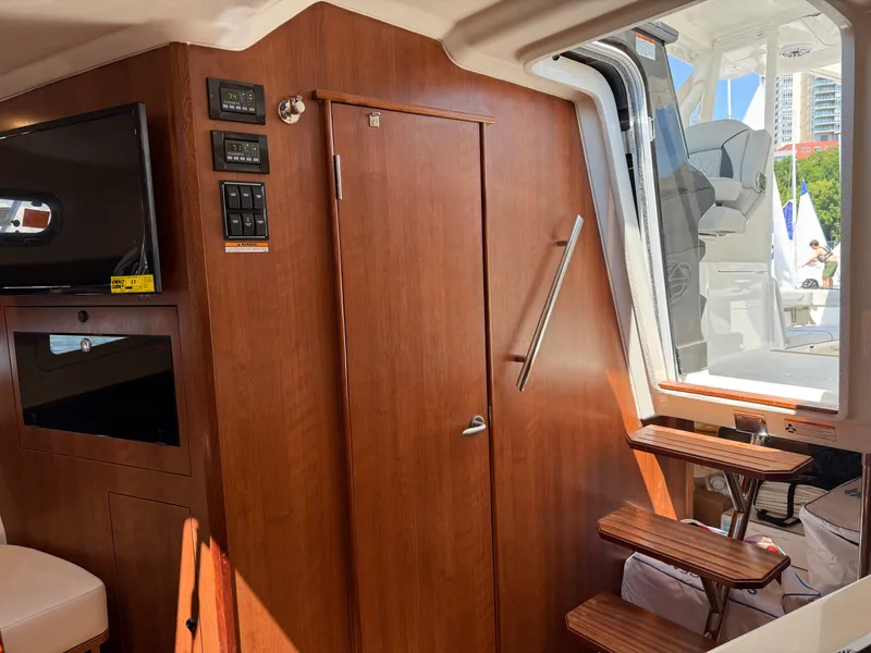 Slide: The Image of Interior of a 2027 Pursuit OS 355 Offshore with wood paneling and stairs leading to the cabin. - 33