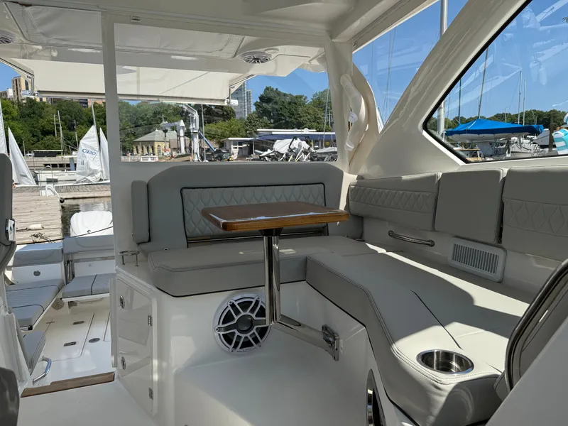 Slide: The Image of Interior of a 2027 Pursuit OS 355 Offshore with gray seating and wooden table at a marina. - 24