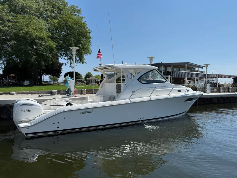 Slide: The Image of Pursuit OS 355 Offshore 2027: Sleek white boat docked with twin outboard engines and spacious cockpit. - 40