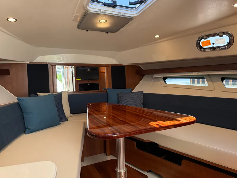Slide: The Image of Interior of a modern yacht with a wooden table, blue cushions, and windows letting in natural light. - 28