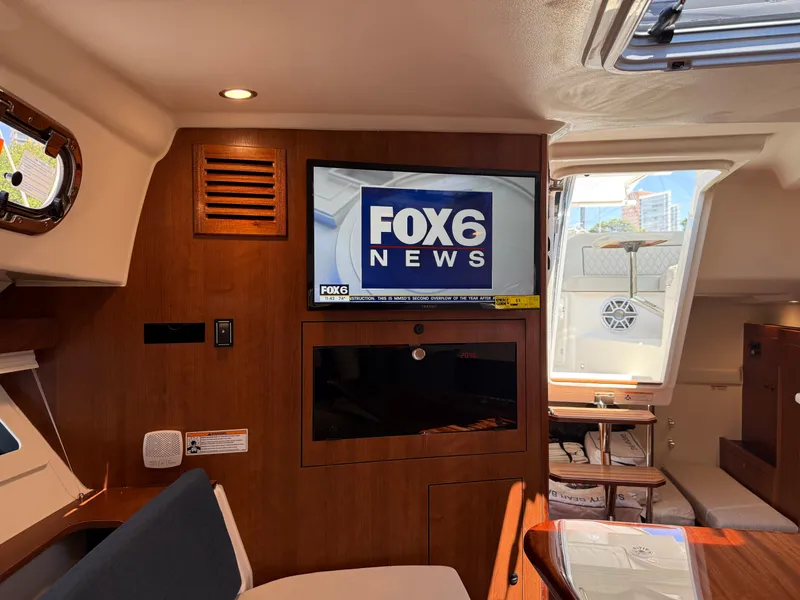 Slide: The Image of Interior of a Pursuit OS 355 Offshore with a TV and wooden furnishings. - 32