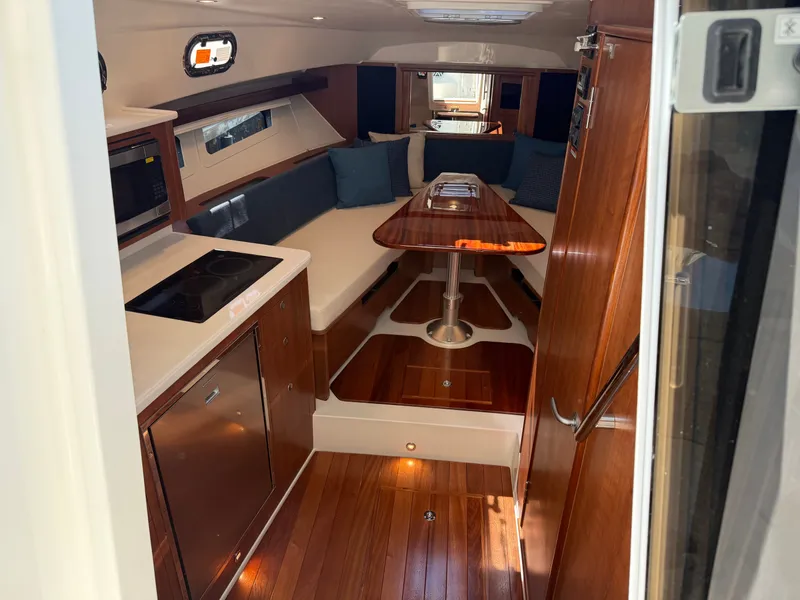 Slide: The Image of The 2027 Pursuit OS 355 Offshore cabin features elegant wood flooring and a dining table. - 27