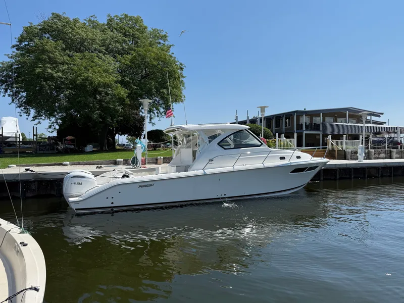 The Image of A white Pursuit OS 355 Offshore boat docked near a house and a tree. - 0
