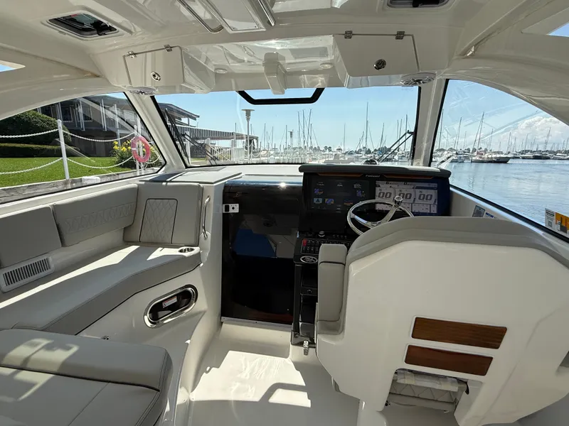 Slide: The Image of The cockpit of a 2027 Pursuit OS 355 Offshore with modern instruments and a panoramic harbor view. - 18