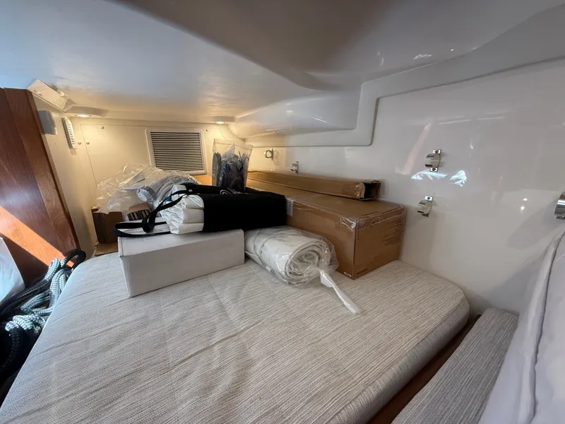 Slide: The Image of Interior of a 2027 Pursuit OS 355 Offshore with cushions and packaged items on a bed. - 39