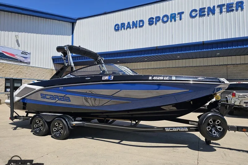 Slide: The Image of 2022 Scarab 255 Wake ID boat at Grand Sport Center, displayed on a trailer. - 14