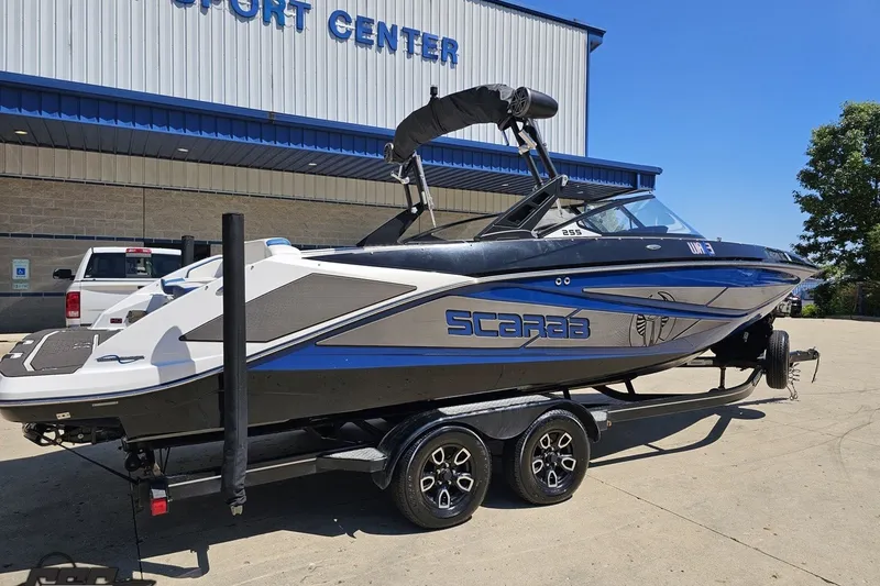 Slide: The Image of 2022 Scarab 255 Wake ID boat on trailer outside a sport center. - 11