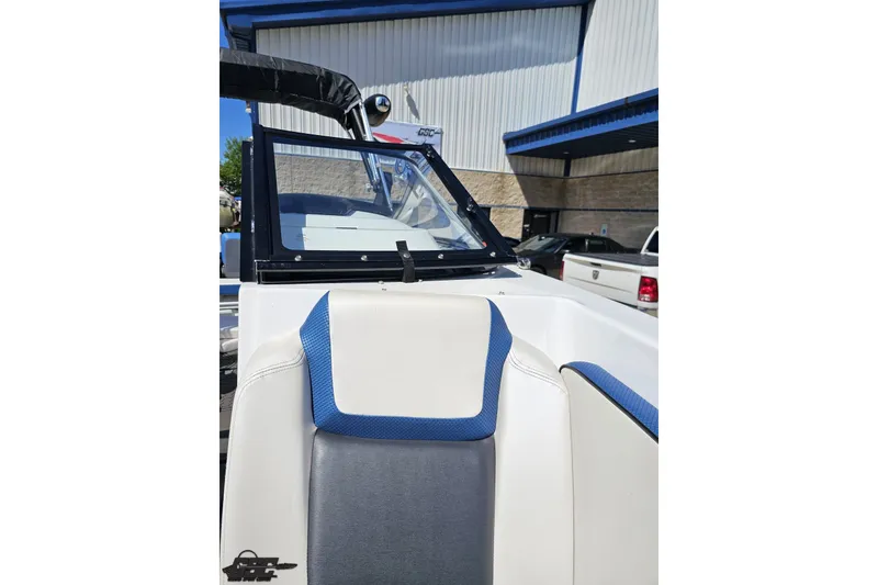 Slide: The Image of 2022 Scarab 255 Wake ID boat interior with blue and white seating, parked outside a building. - 102
