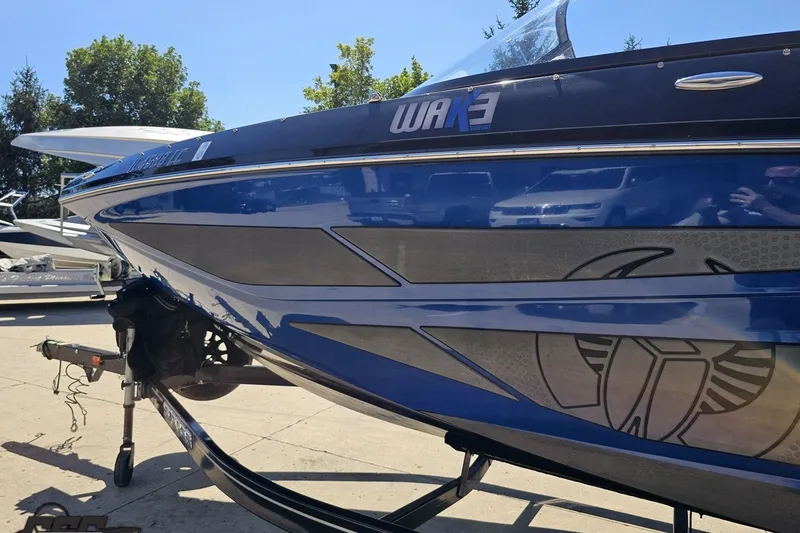 Slide: The Image of 2022 Scarab 255 Wake ID boat, blue and silver design, parked outdoors. - 25