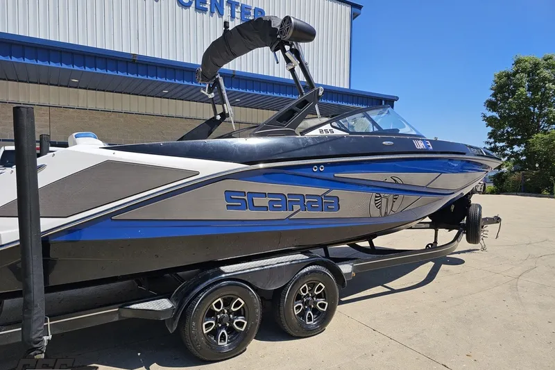Slide: The Image of 2022 Scarab 255 Wake ID boat on trailer, parked outside a building. - 10