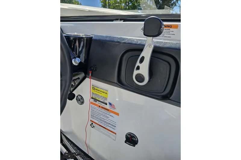 Slide: The Image of Interior view of 2022 Scarab 255 Wake ID boat dashboard with control lever and warning labels. - 78