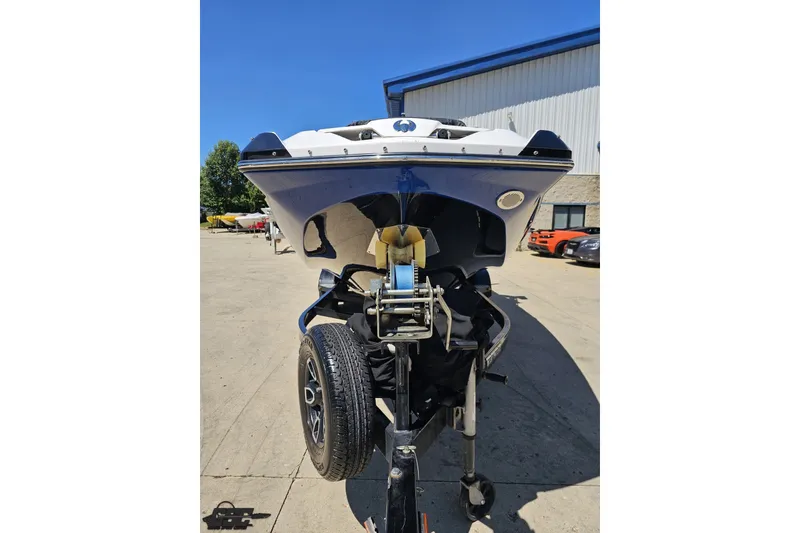 Slide: The Image of 2022 Scarab 255 Wake ID boat on trailer, parked outdoors under clear blue sky. - 16
