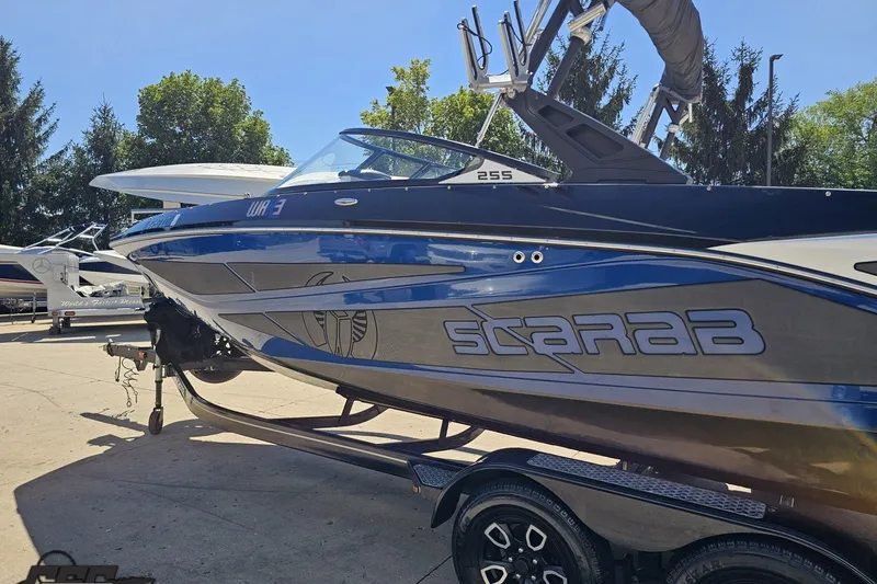 Slide: The Image of 2022 Scarab 255 Wake ID boat on trailer, sleek design, blue and silver finish. - 27