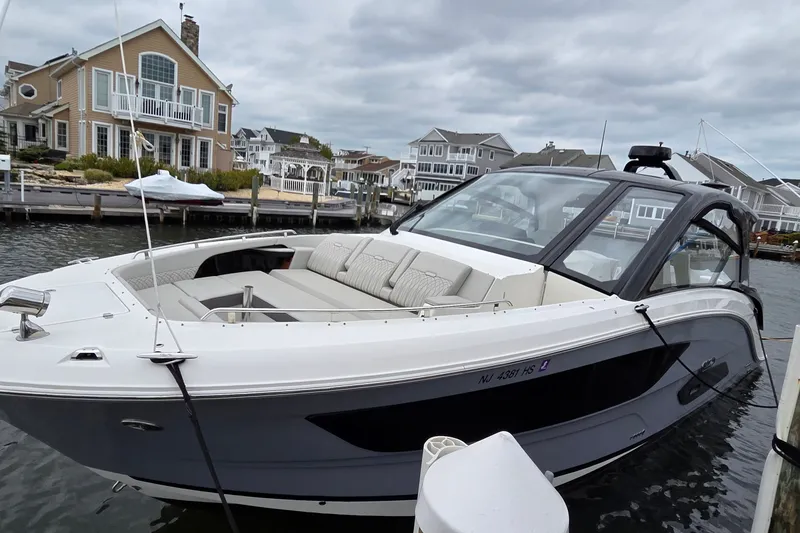 Slide: The Image of 2023 Sea Ray Sundancer 370 Outboard docked near waterfront homes under cloudy skies. - 10