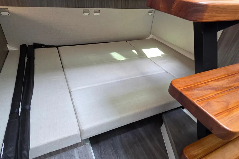 Slide: The Image of 2023 Sea Ray Sundancer 370 Outboard cabin interior with beige seating and wooden accents. - 22