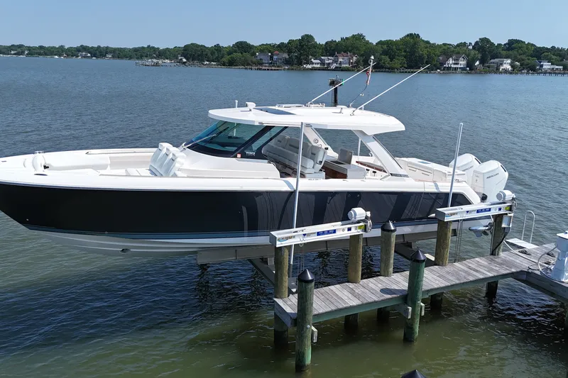 Slide: The Image of 2025 Tiara Yachts 43 LS docked on a serene lake with lush greenery. - 2