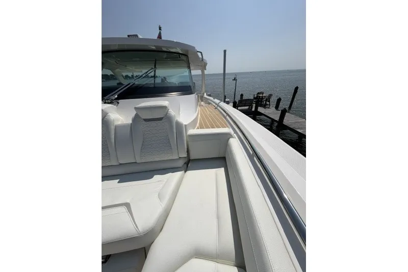 Slide: The Image of 2025 Tiara Yachts 43 LS luxury boat with white seating, docked by the water. - 10