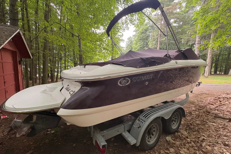 Slide: The Image of 2006 Cobalt 220 boat on trailer in wooded area, covered and ready for transport. - 8