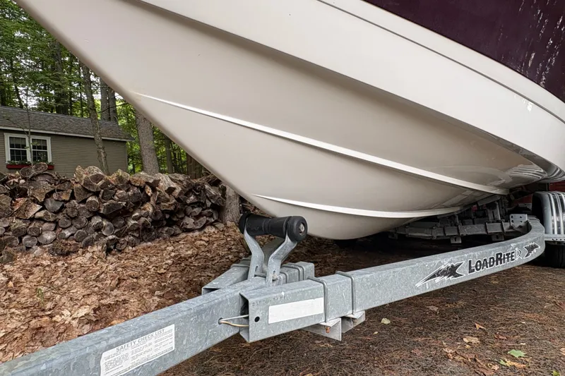 Slide: The Image of 2006 Cobalt 220 boat on Load Rite trailer, parked near woodpile in wooded area. - 13