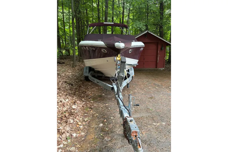 Slide: The Image of 2006 Cobalt 220 boat on trailer in wooded area near red shed. - 9