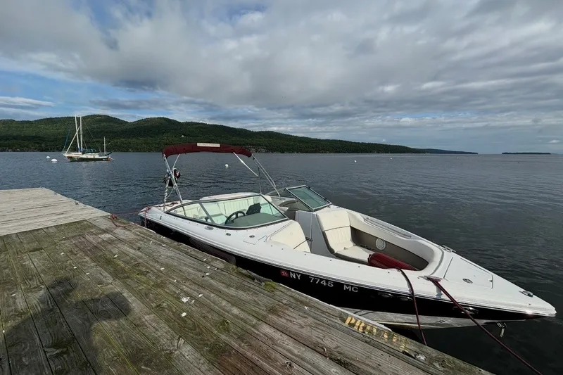 Slide: The Image of 2006 Cobalt 220 boat docked on a serene lake with scenic hills in the background. - 1