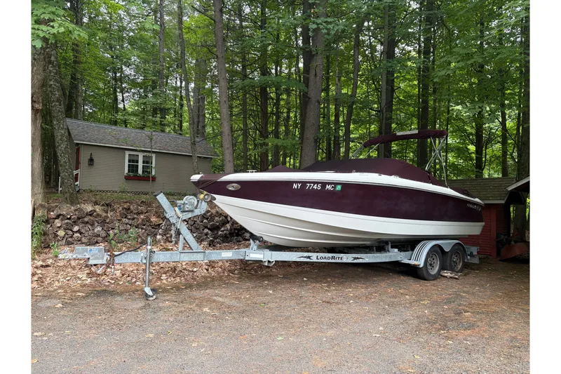 Slide: The Image of 2006 Cobalt 220 boat on trailer in wooded area near cabin. - 4