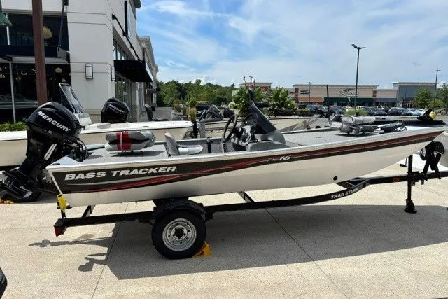 The Image of 2010 Tracker Pro 16 bass boat on trailer, parked outdoors, featuring Mercury outboard motor. - 0