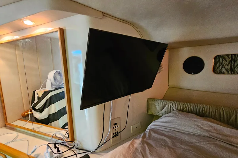 Slide: The Image of Interior of a 1995 Sea Ray 500 Sundancer with mounted TV and cozy bedding. - 36