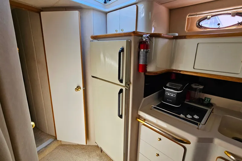 Slide: The Image of 1995 Sea Ray 500 Sundancer yacht interior kitchen with fridge, stove, and cabinets. - 32