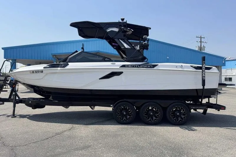 The Image of 2025 Centurion Ri245 boat on trailer, sleek design, parked near blue building. - 0