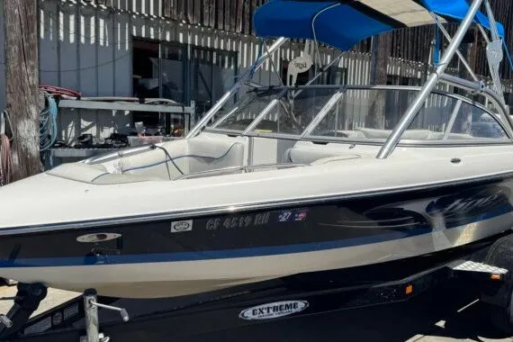 Slide: The Image of 2006 Tige 22i boat with blue canopy on trailer, parked outdoors. - 6