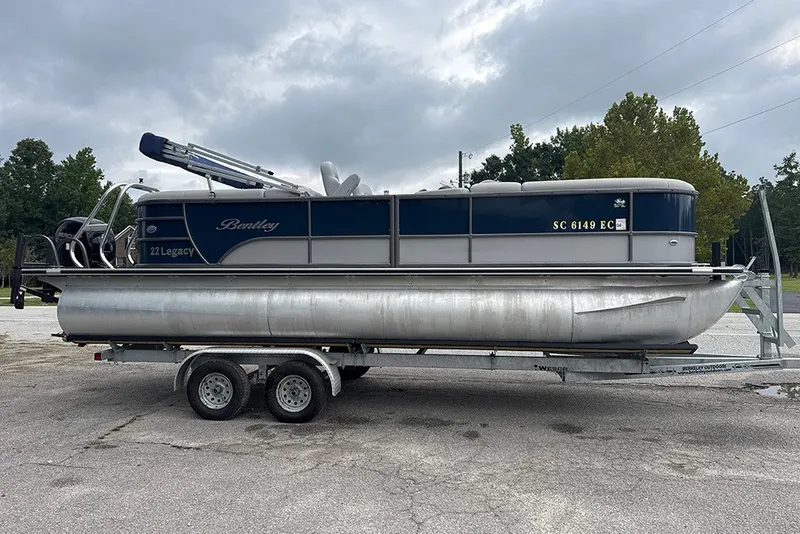 Slide: The Image of 2023 Bentley Pontoons Legacy Navigator 223 on trailer, parked outdoors under cloudy sky. - 3