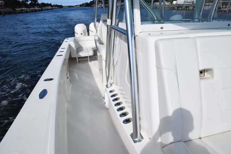 Slide: The Image of 2022 SeaVee 390Z boat interior with sleek white seating and rod holders on a calm waterway. - 17