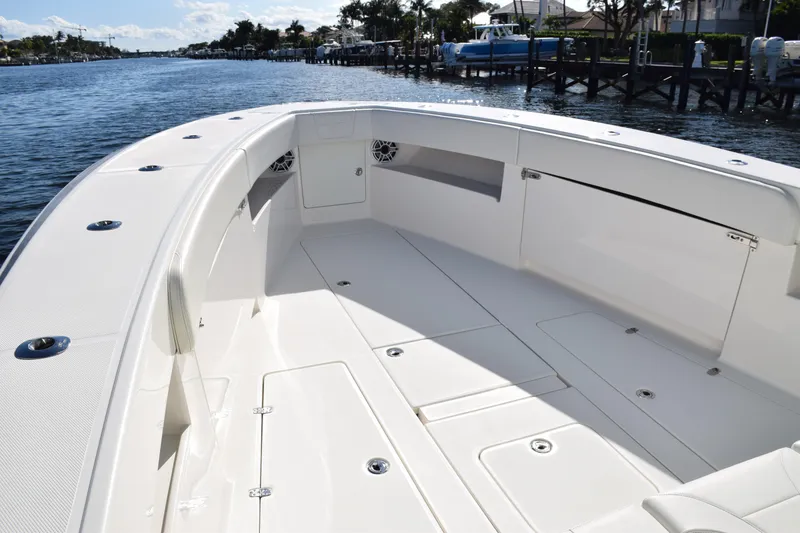 Slide: The Image of 2022 SeaVee 390Z boat deck with spacious seating and storage, docked by a scenic waterfront. - 32