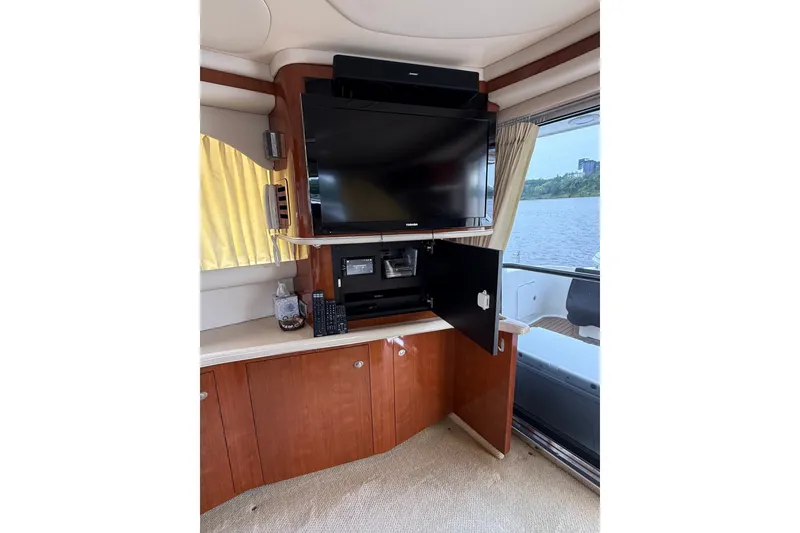 Slide: The Image of Interior of 2004 Sea Ray 480 Sedan Bridge with TV and wooden cabinetry. - 23
