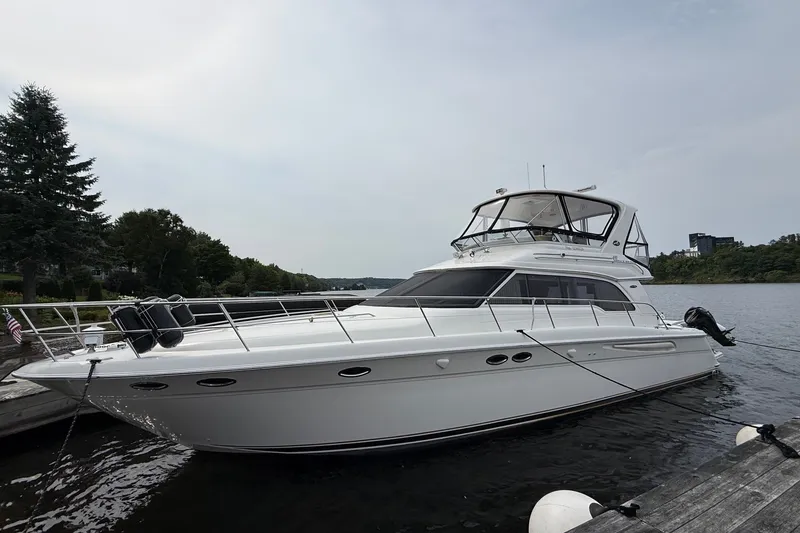 The Image of 2004 Sea Ray 480 Sedan Bridge yacht docked on a calm lake. - 0